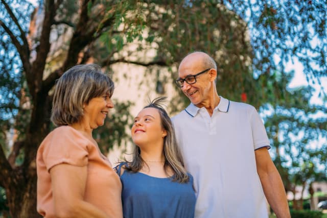 Família unida satisfeita, pai, mãe e filha com deficiência sorrindo.